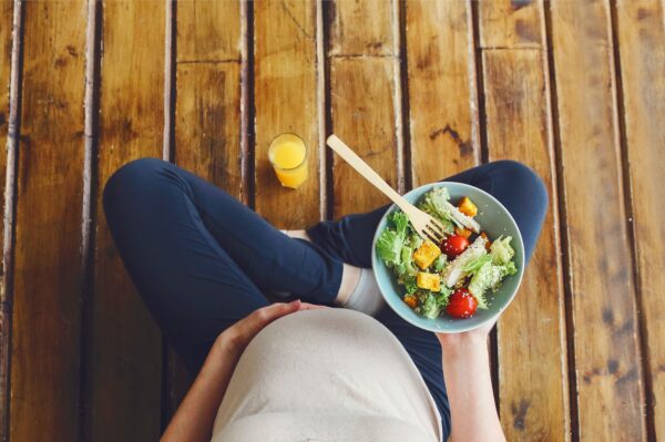 Overhead view of pregnant woman with a bowl of nutritional food